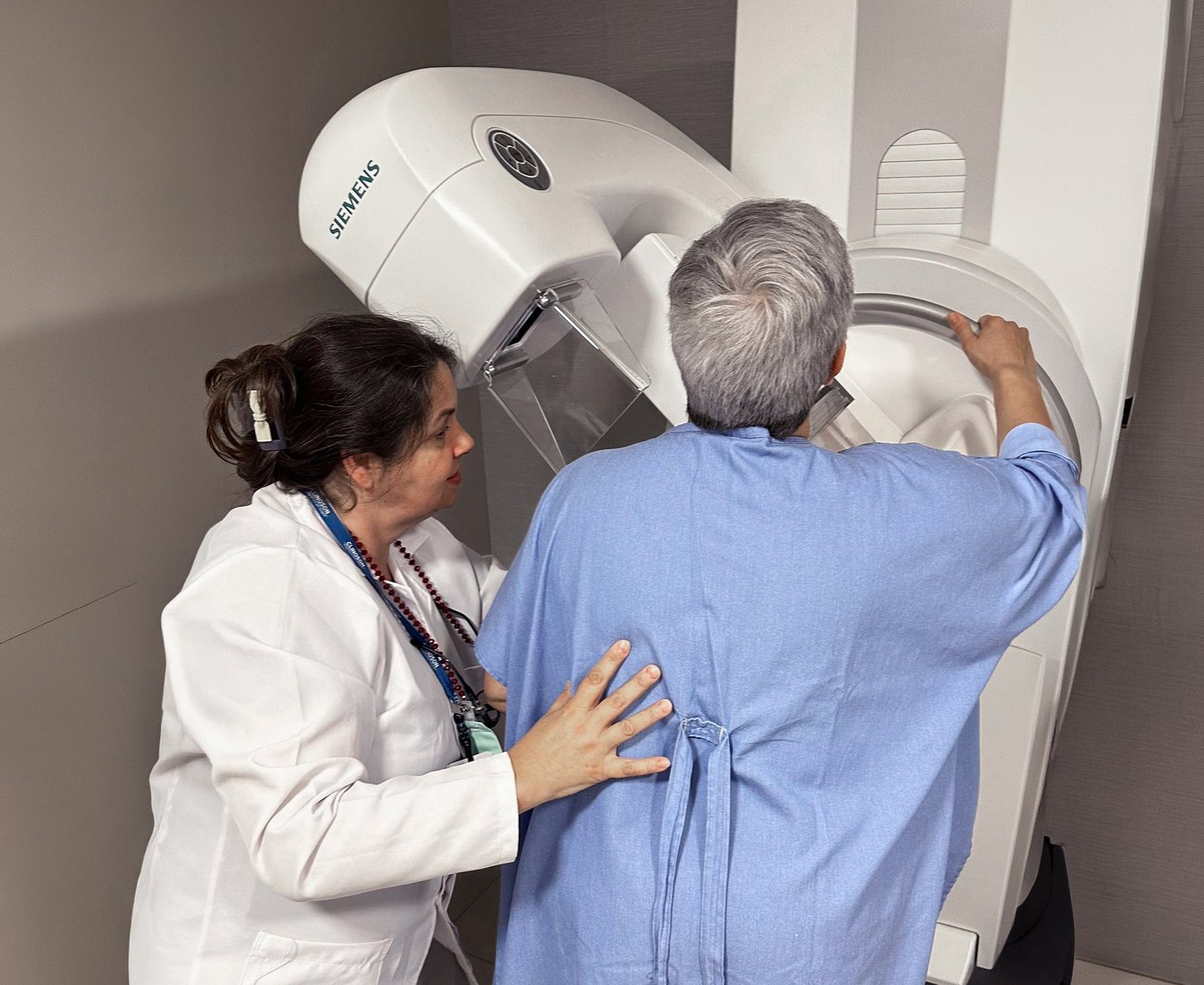Técnica posicionando paciente no mamógrafo Siemens